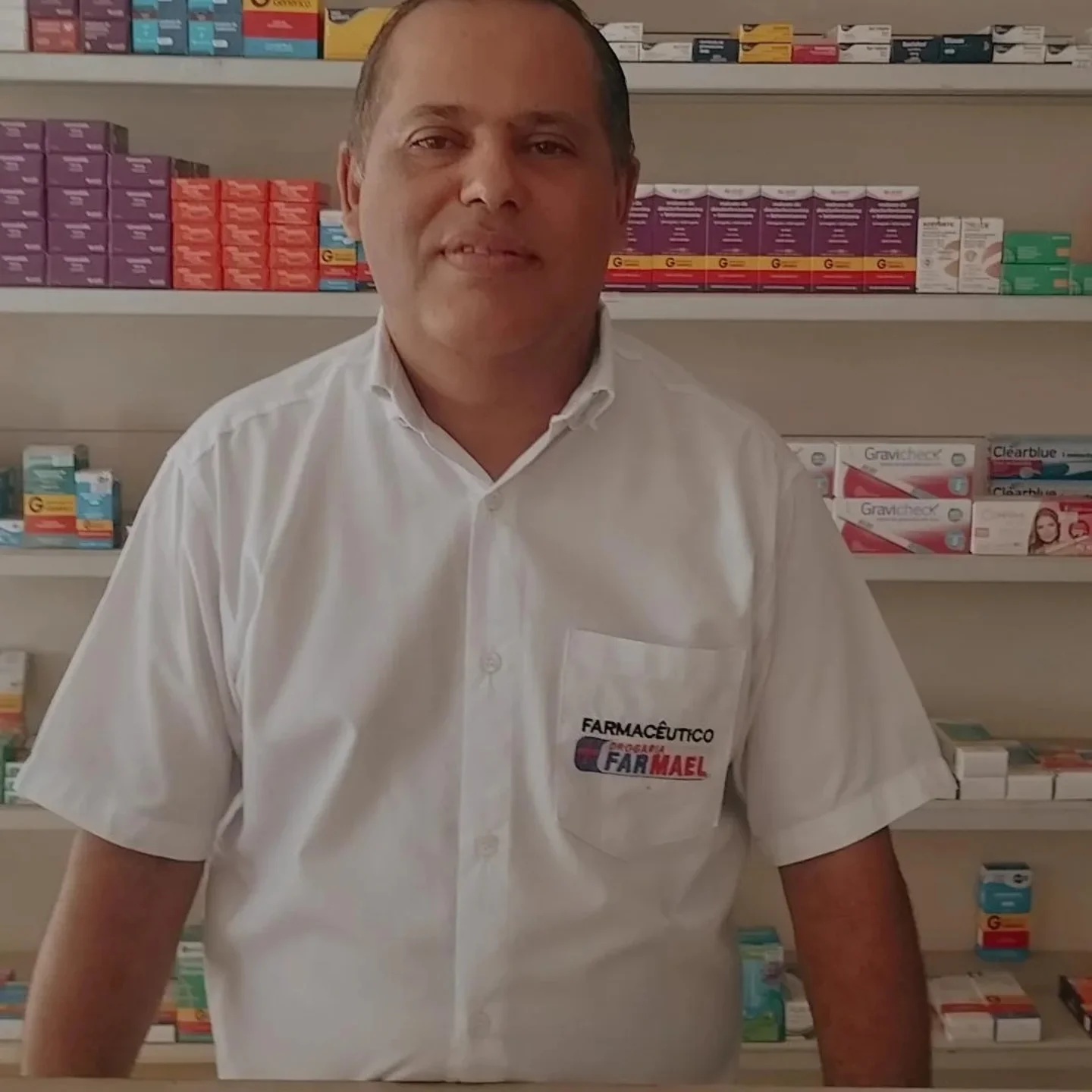 Profissional da Farmael na drogaria, diante das prateleiras de medicamentos